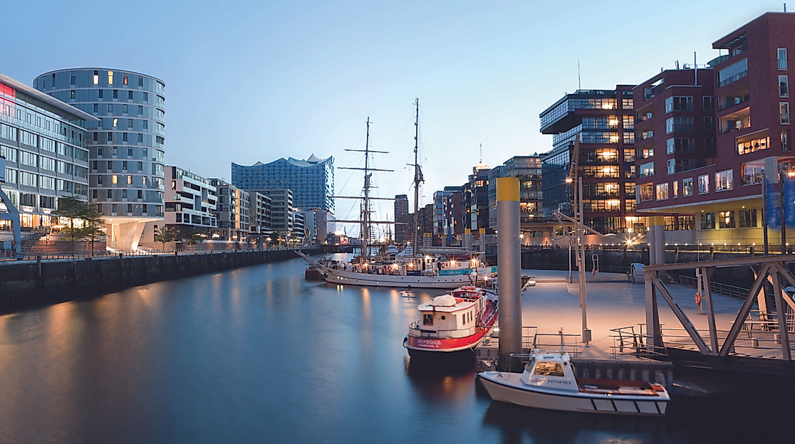Abendstimmung im Sandtorhafen der HafenCity Hamburg mit beleuchteten Gebäuden, Booten und Traditionssegler