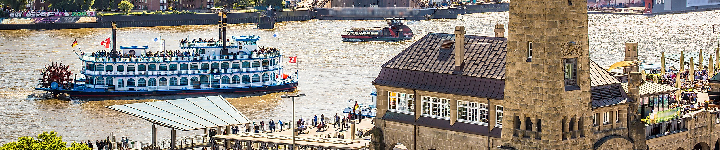 Blick auf die St. Pauli Landungsbrücken mit Hafenfähre und Hamburger Hafen, beliebter Startpunkt barrierefreier Touren