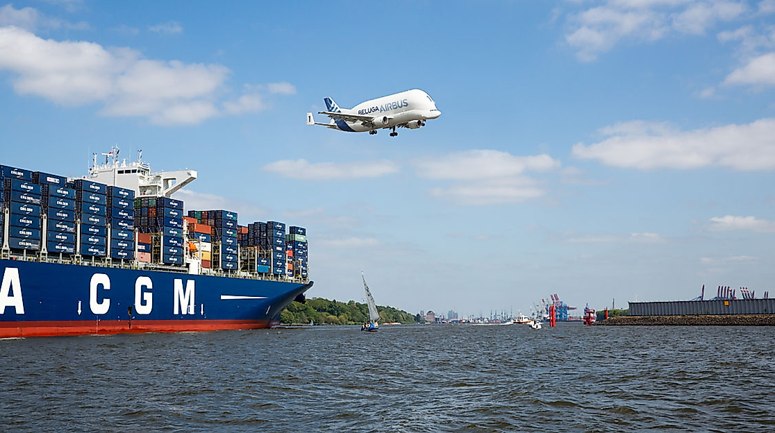 Beluga-Flugzeug über einem Containerschiff