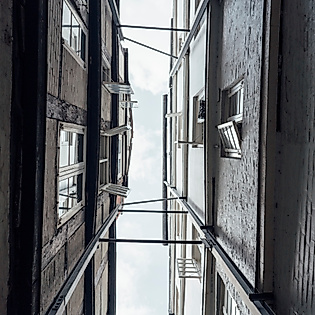 Blick nach oben zwischen engen Fassaden historischer Gebäude in einer Hamburger Gasse.