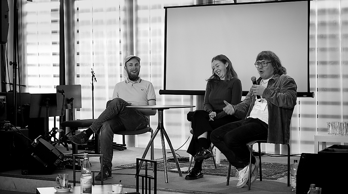 Three people are sitting on a panel and talking.