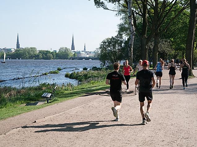 Jogger und Spaziergänger auf dem Alsteruferweg bei sommerlichem Wetter in Hamburg