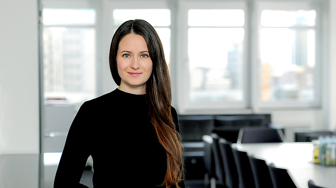 Porträt einer Frau mit langen dunklen Haaren im schwarzen Outfit vor hellem Konferenzraum, Ansprechpartnerin der Hamburg Tourismus GmbH