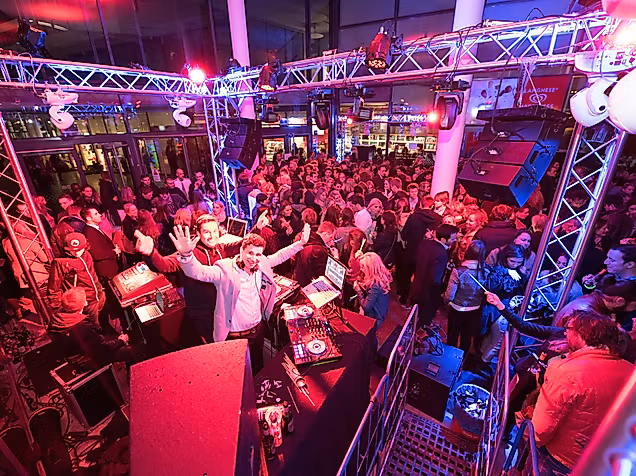 DJ-Pult mit Plattenspielern in der Sunset Lounge Disco, umgeben von buntem Licht und Partystimmung