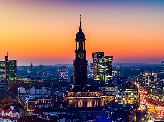 Baroque tower of Hamburg's Michel Church in front of the skyline at sunset. 