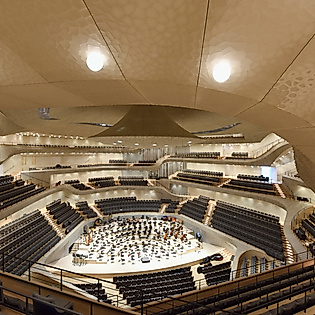 Großer Saal der Elbphilharmonie: tief und zentral liegt die Bühne, darüber ein großer Klangreflektor, umgeben von terrassenförmigen Publikumsrängen