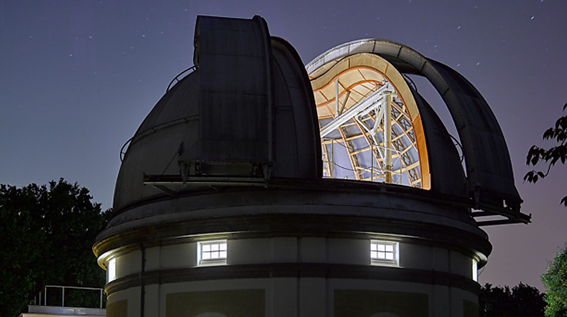 Beleuchtete Kuppel der Hamburger Sternwarte in Bergedorf bei Nacht mit geöffnetem Teleskopdach