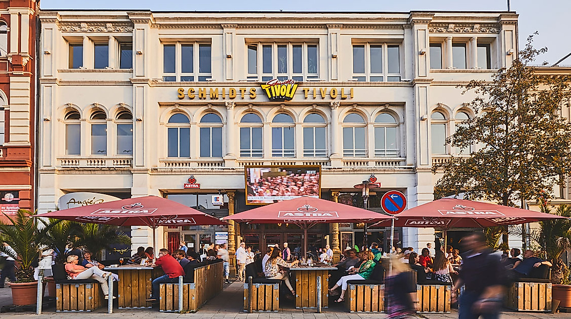 Außenansicht des Schmidts Tivoli Theaters auf der Reeperbahn in Hamburg mit Außengastronomie und markanter Fassade.