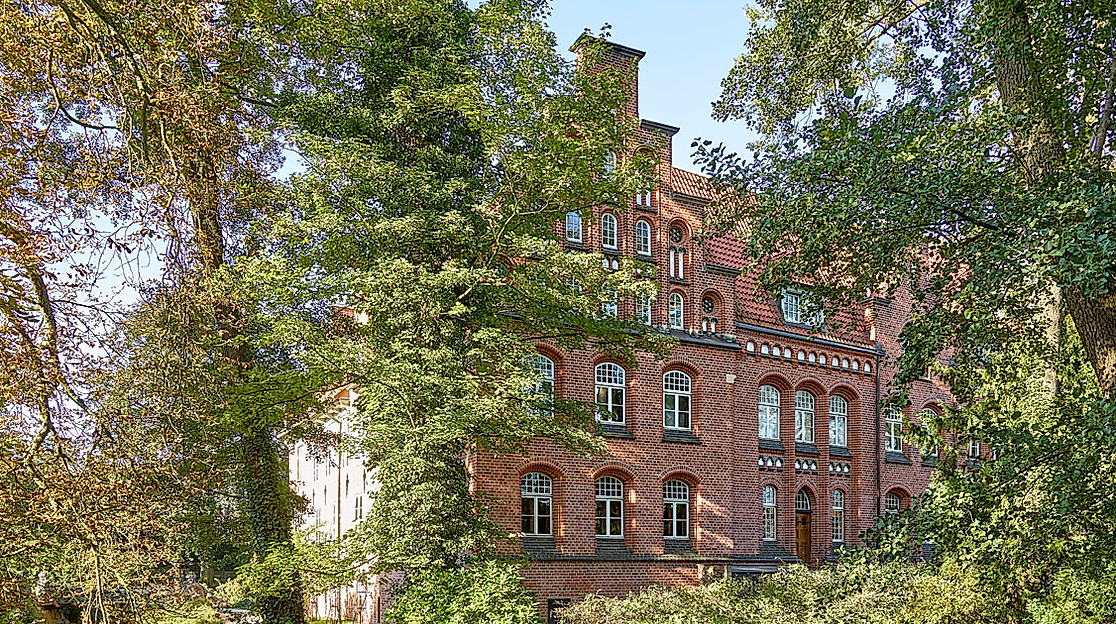 Teilansicht des Bergedorfer Schlosses in Hamburg hinter dichtem Grün an einem sonnigen Tag