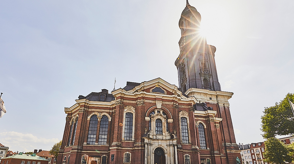 Fassade der Barockkirche St. Michaelis mit Sonnenschein hinter dem Kirchturm in Hamburg