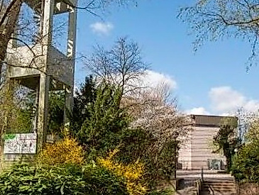 Kirchturm mit grünen Sträucher und im Hindergrund Kirchengebäude