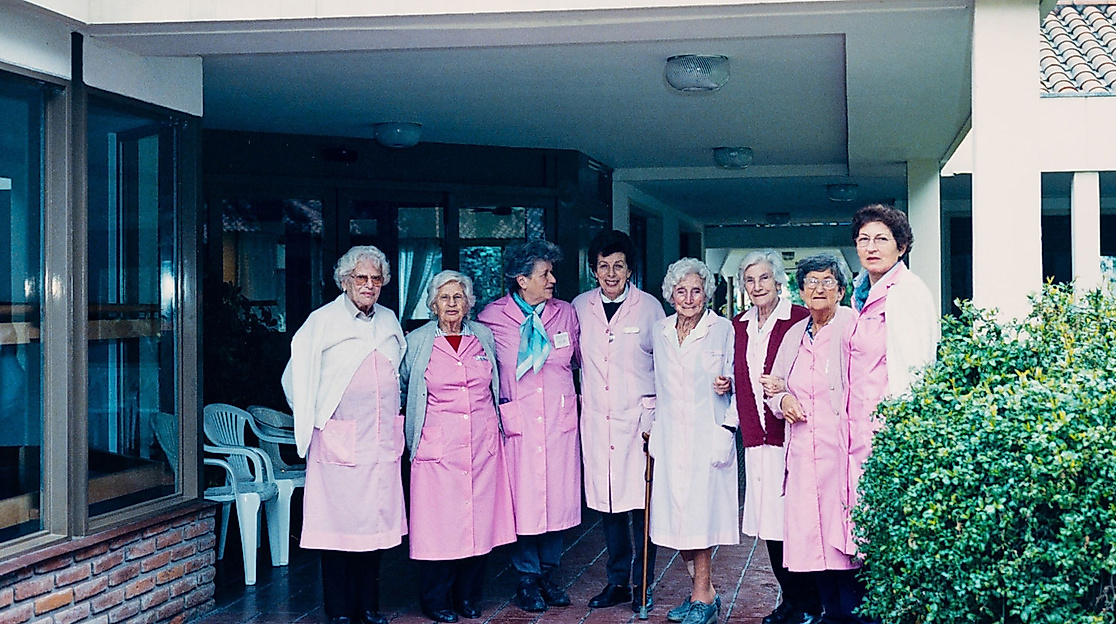 Frauen in rosa Kitteln vor Gebäude