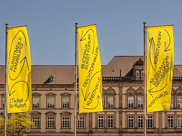Gelbe Kunstmeile-Fahnen vor klassizistischer Fassade am Hamburger Glockengießerwall bei blauem Himmel