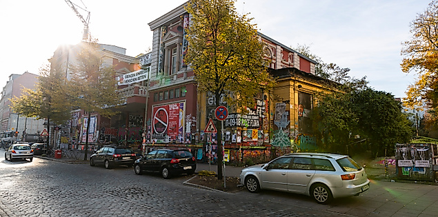 Straßenszene im Hamburger Schanzenviertel mit Graffiti-Fassade, Kopfsteinpflaster und herbstlich belaubten Bäumen.