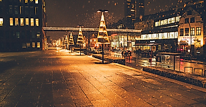 Christmas lights reflecting on wet cobblestones at night in a festively lit Hamburg street