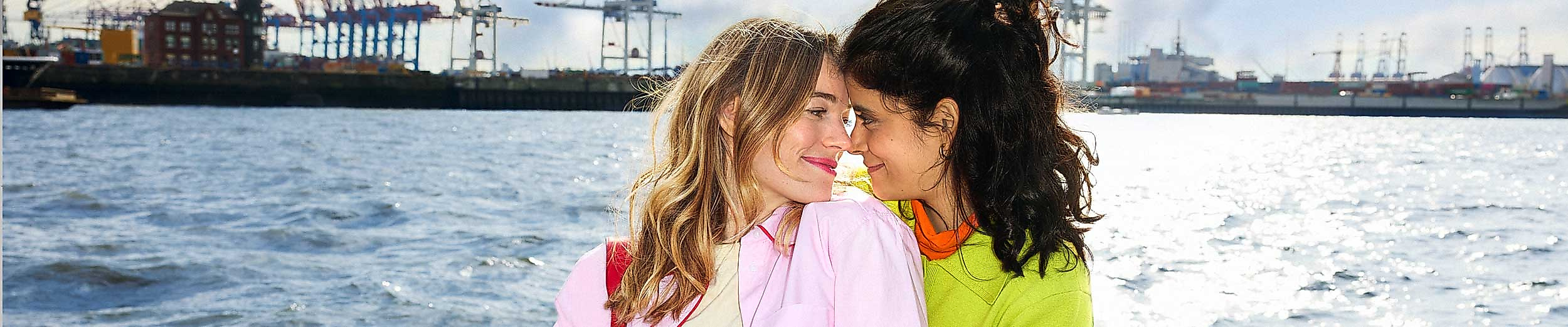 Zwei der LGBTQIA+ Community angehörige Frauen sitzen am Hamburger Hafen