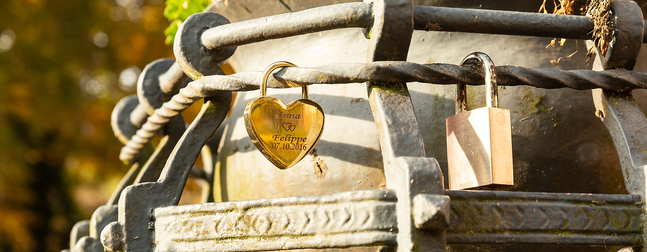Liebesschlösser an einem historischen Brunnen in Hamburg-Bergedorf, umgeben von Blumen und Herbstlaub.