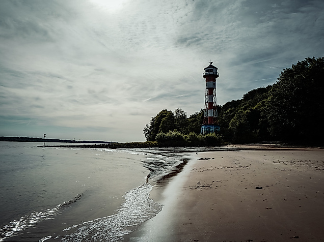 Leuchtturm Wittenbergen am Elbstrand mit nassem Sand, flachen Wellen und bewölktem Himmel