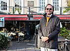 Andre Hallier mit Sonnenbrille vor Restaurantterrasse in Hamburg bei Sonnenschein