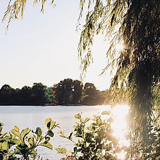 Sonnenuntergang über der Hamburger Außenalster mit Blick auf die Stadtsilhouette und Kirchtürme