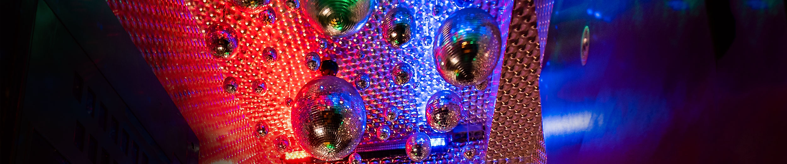 Decke mit Spiegelkugeln und bunten LED-Lichtern sorgt für dynamische Stimmung in Hip-Hop-Club.