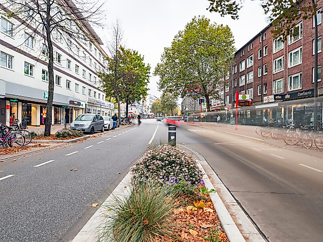 Osterstraße in Hamburg-Eimsbüttel mit Radweg, Herbstbäumen und Geschäften auf beiden Seiten