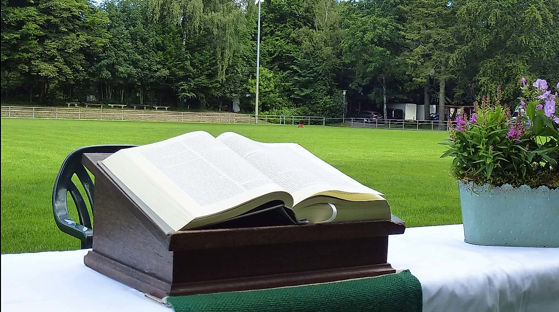 Aufgeschlagene Bibel und Blumenkorb auf einem Altar auf dem Fußballfeld