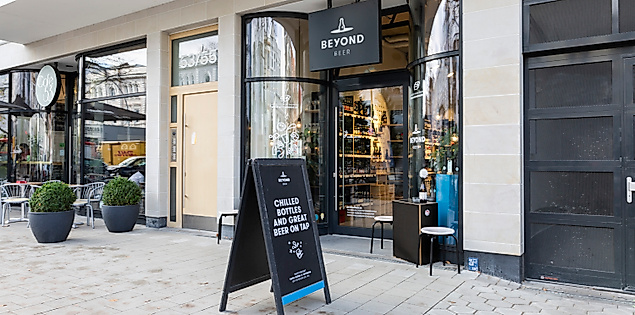 Außenansicht des Craft Beer Stores Beyond Beer in Hamburg mit Glasfassade, schwarzem Aufsteller und modernem Design