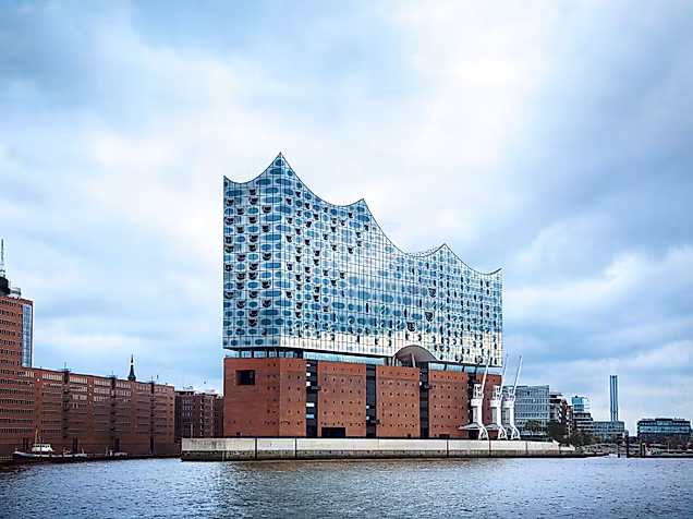 Elbphilharmonie in Hamburg mit gläserner Wellenarchitektur und Backsteinsockel am Wasser