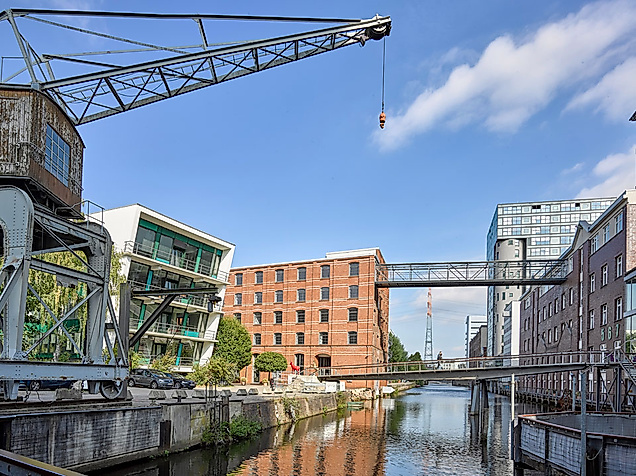 Moderner und historischer Backsteinbau am Kanal in Hamburg-Harburg mit Fußgängerbrücken und Spiegelung im Wasser