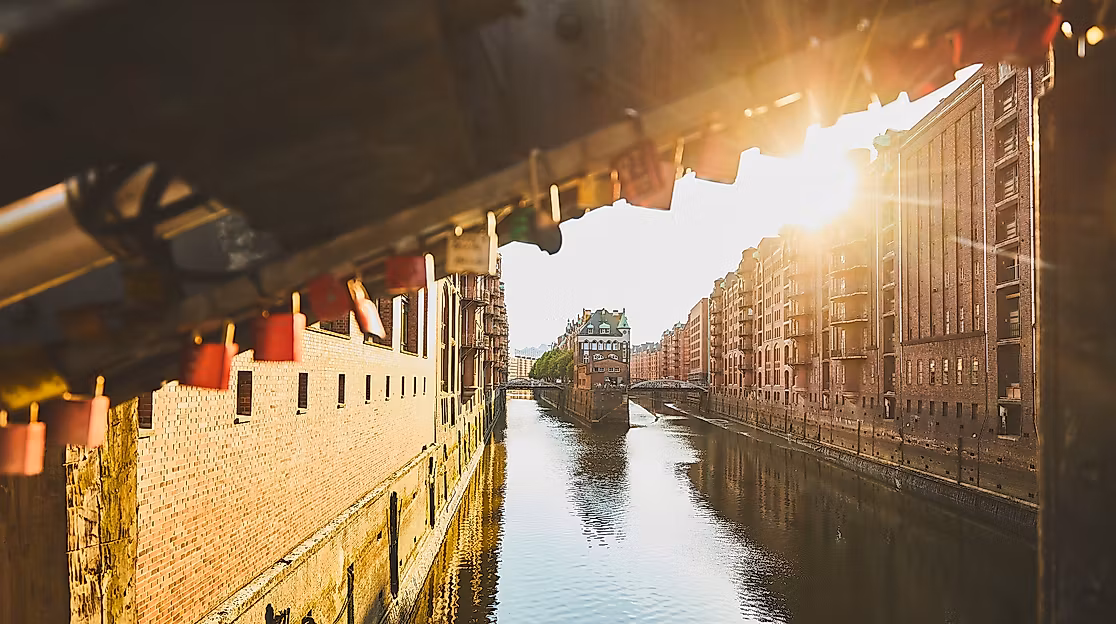 Blick auf das Wasserschloss in der Speicherstadt bei tief stehender Sonne, warmes Licht im Fleet gespiegel