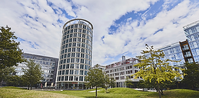 Magellanterrassen in der HafenCity Hamburg mit Grünfläche, Bäumen und modernem Wohnturm im Hintergrund