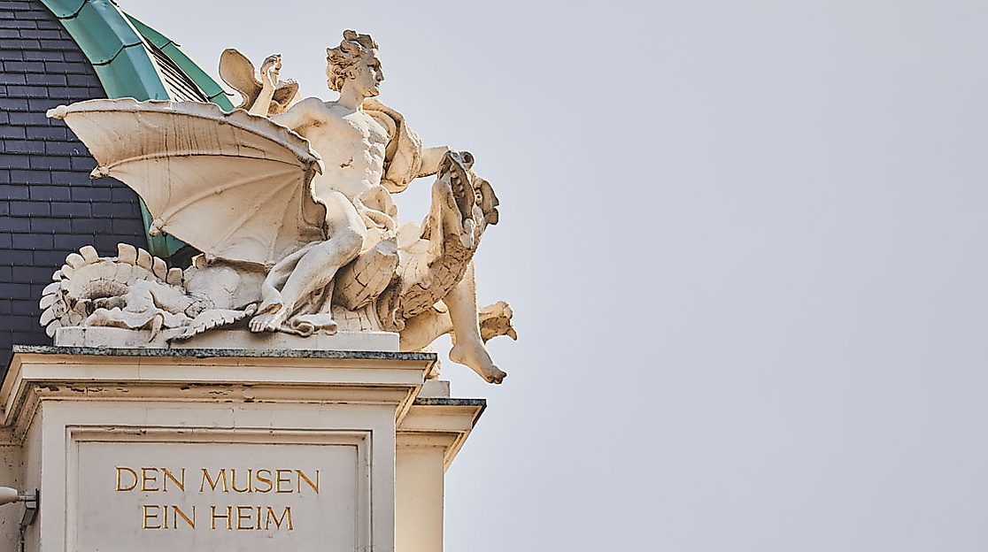 Detailansicht der Statue eines Engels auf der Fassade des Deutschen Schauspielhauses in Hamburg, darunter in den Stein eingraviert Den Musen ein Heim