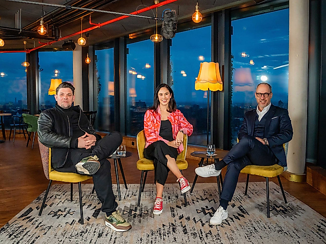 Tim Mälzer, Michael Otremba und eine Moderatorin sitzen entspannt in Lounge-Atmosphäre mit Panorama-Ausblick beim Hamburg Horizonte Talk