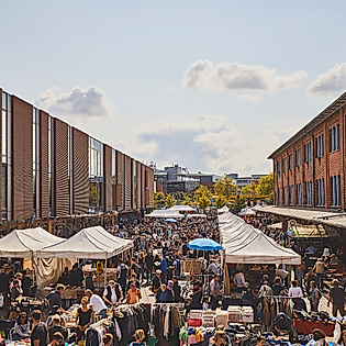 Dichter Trubel zwischen Ständen und Backsteinfassaden beim Flohmarkt Flohschanze am Lattenplatz in Hamburg