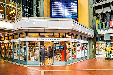 Eingang der Tourist-Information im Hauptbahnhof Hamburg mit großem Infoschild und digitaler Anzeigetafel.