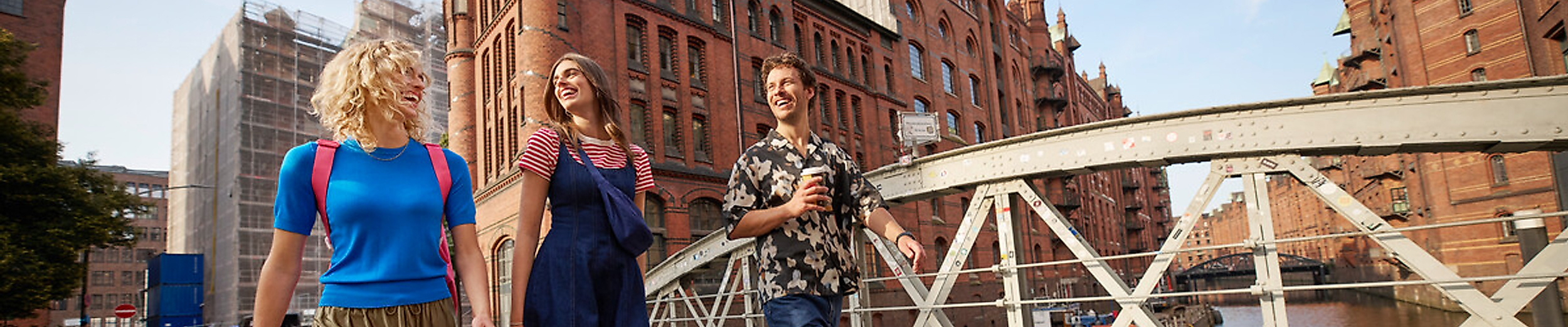 Drei Menschen flanieren über eine Brücke in der Speicherstadt Hamburg