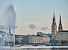 Blick über die Binnenalster auf das Hamburger Rathaus und die Alsterfontäne bei Abendlicht