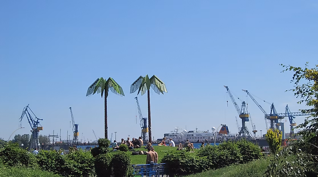 Künstliche Palmen im Park Fiction mit Blick auf den Hamburger Hafen und Hafenkräne bei blauem Himmel