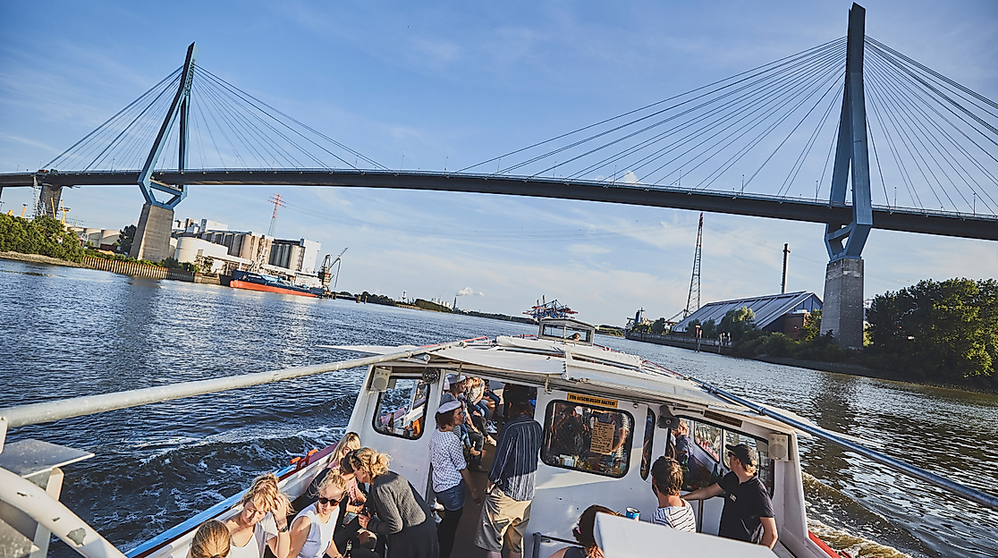 Fahrgastschiff unterquert die Köhlbrandbrücke im Hamburger Hafen bei blauem Himmel