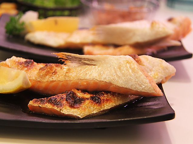 Gegrillte Fischfilets mit Zitronenscheiben auf dunklen Tellern appetitlich angerichtet