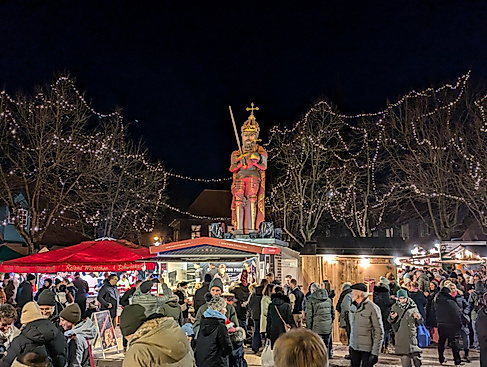 Menschenmenge beim Wedeler Weihnachtsmarkt am Roland mit Weihnachtsbeleuchtung und Ständen