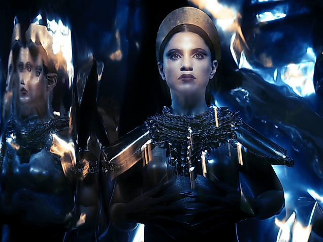 Umgeben von verspiegelter Fläche ist der geschminkte Kopf einer Person zu sehen mit Headpiece und refklektierendem Kostüm.