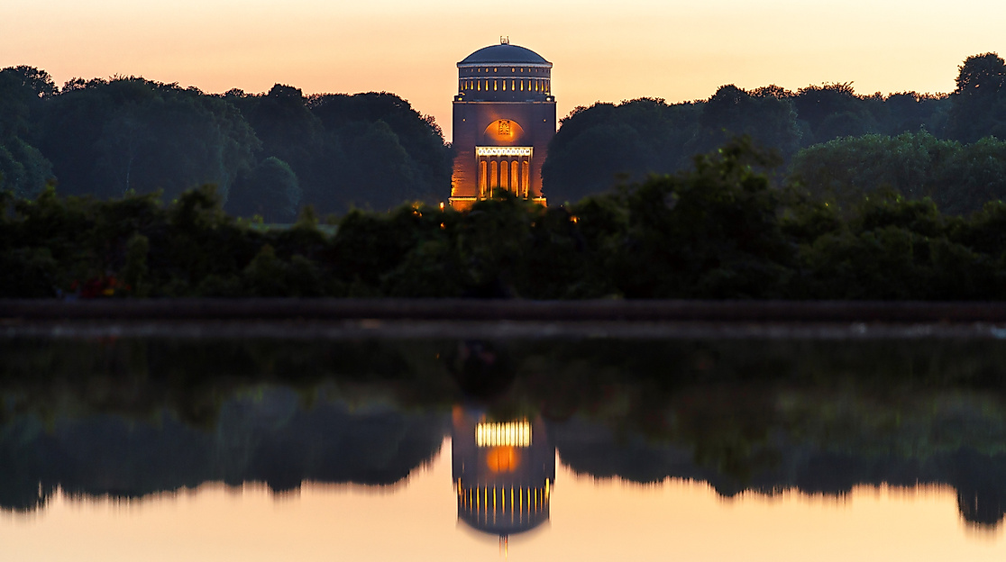 Beleuchteter Wasserturm im Hamburger Stadtpark bei Sonnenuntergang mit Spiegelung im Wasser