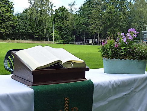 Aufgeschlagene Bibel und Blumenkorb auf einem Altar auf dem Fußballfeld