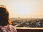 Person blickt bei Sonnenuntergang über das Stadtpanorama von Hamburg.