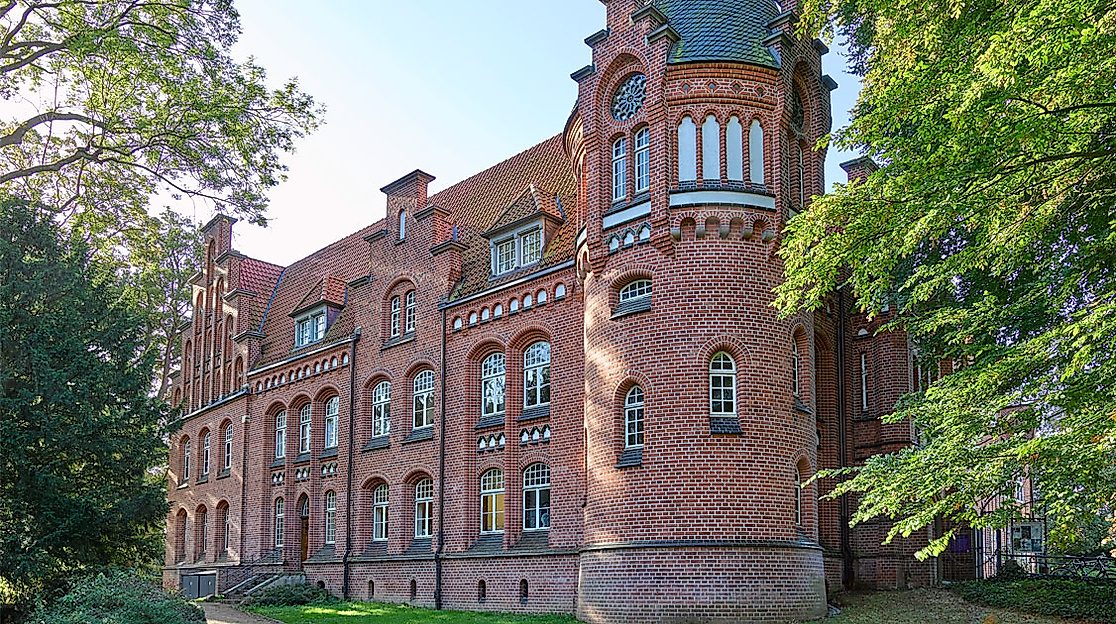 Backsteinfassade des Harburger Schlosses in Hamburg, umgeben von herbstlich gefärbten Bäumen.