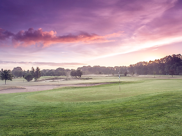Weitläufige Golfanlage Gut Wulfsmühle bei Hamburg im Morgenlicht mit gepflegtem Fairway und Baumkulisse