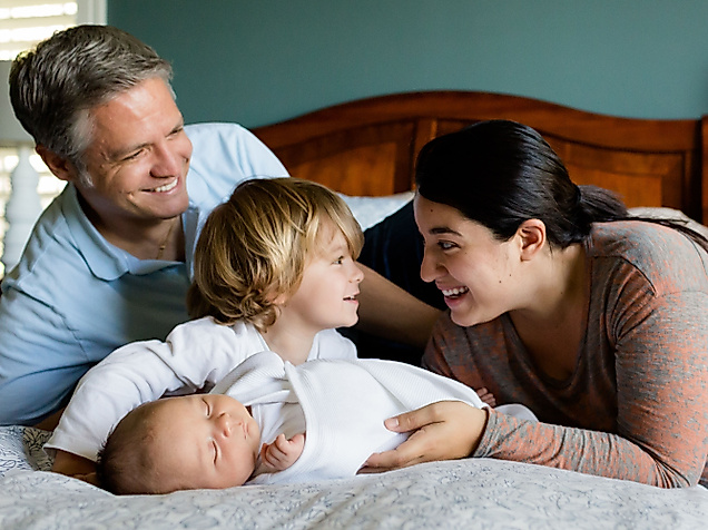 Mann, Frau und zwei Kinder zusammen auf einem Bett