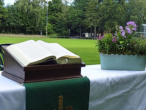 Aufgeschlagene Bibel und Blumenkorb auf einem Altar auf dem Fußballfeld